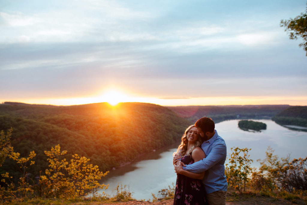 man hugging woman from behind at sunset