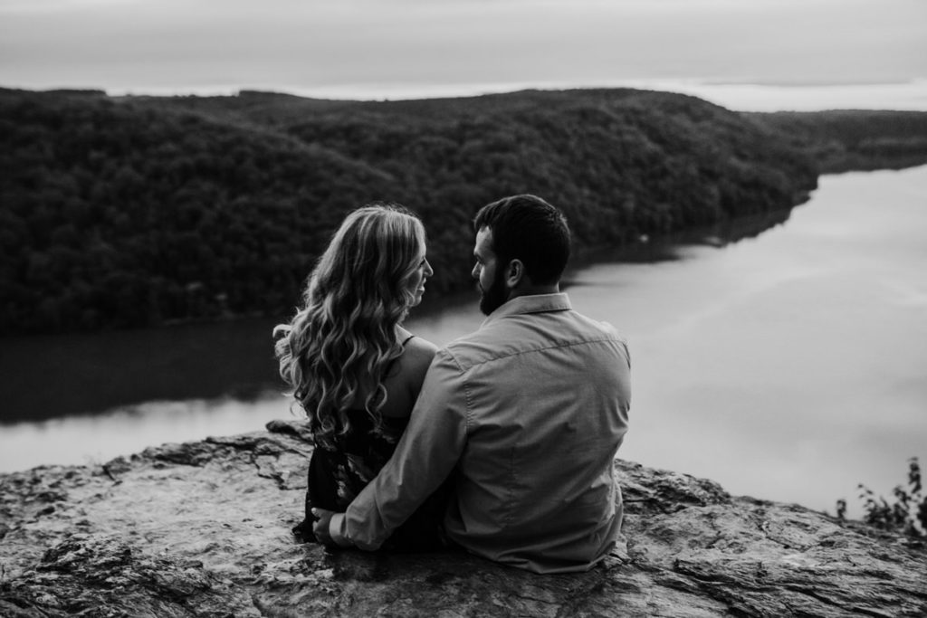 man and woman sitting on a rock on the edge of an overlook