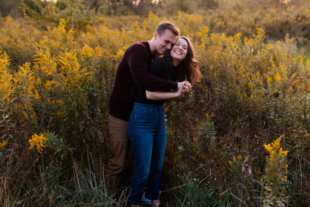 man hugging woman from behind as they are standing in a field