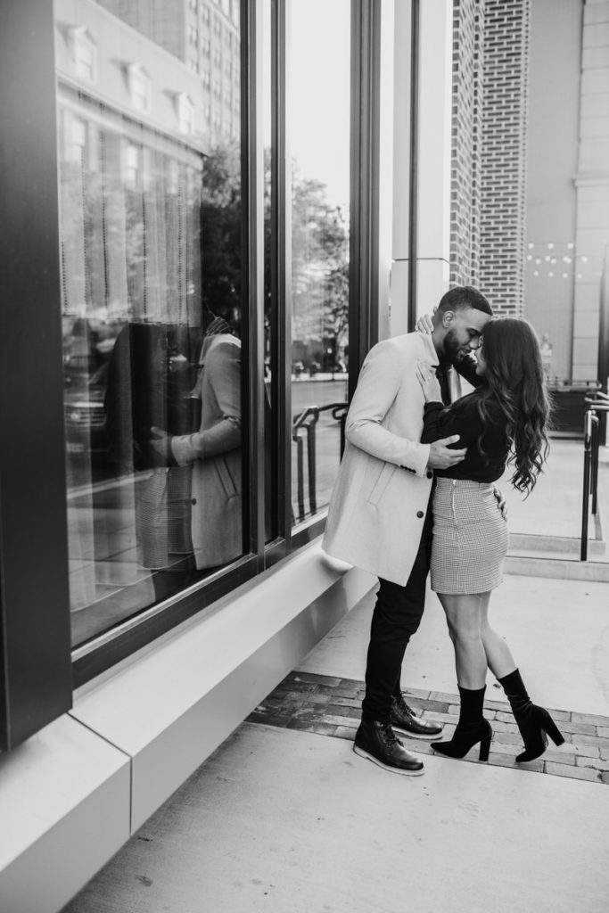 man and woman kissing on a city sidewalk