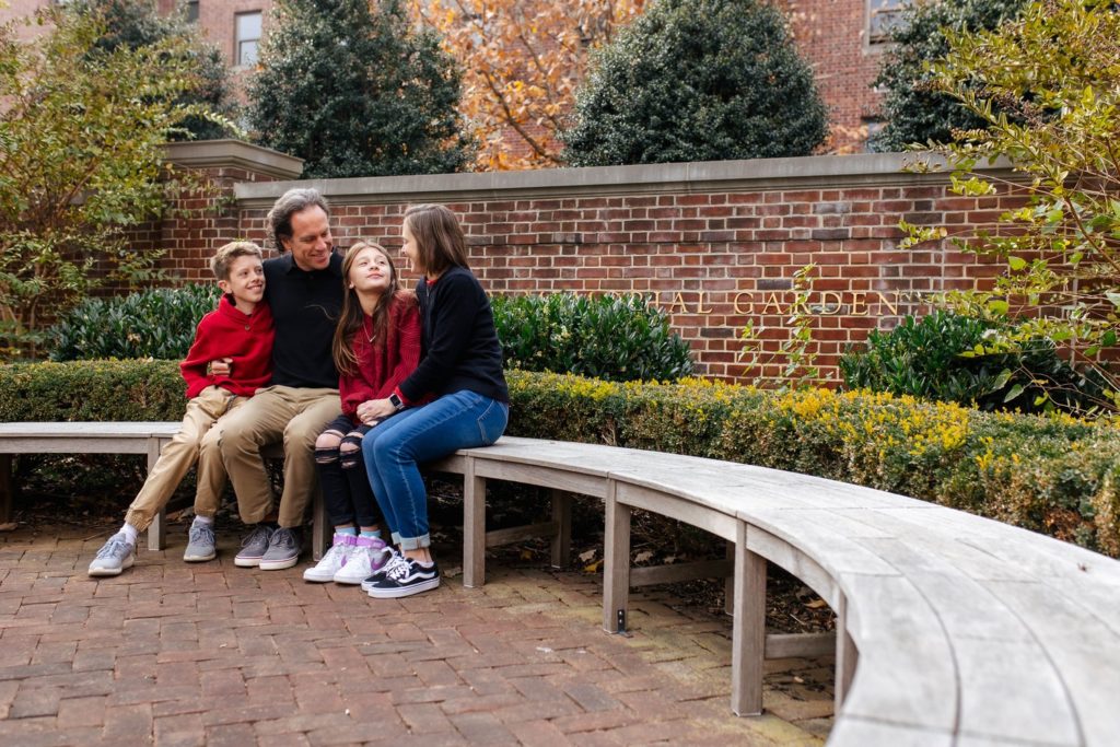 parents and two children sitting on a bench smiling at each other