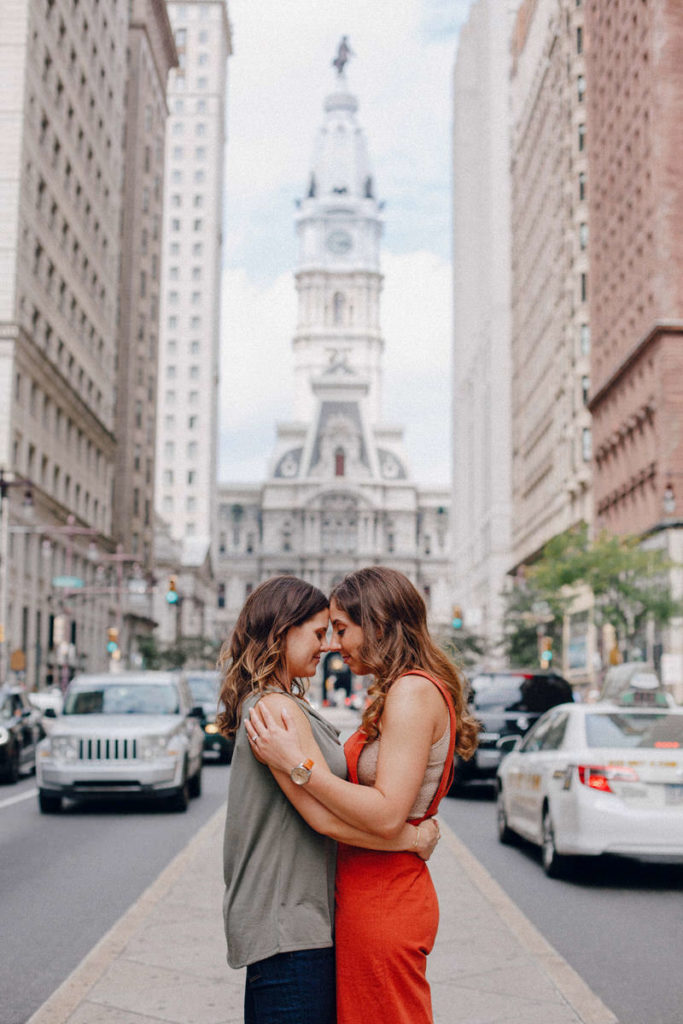 two women hugging each other and touching foreheads while on a city street