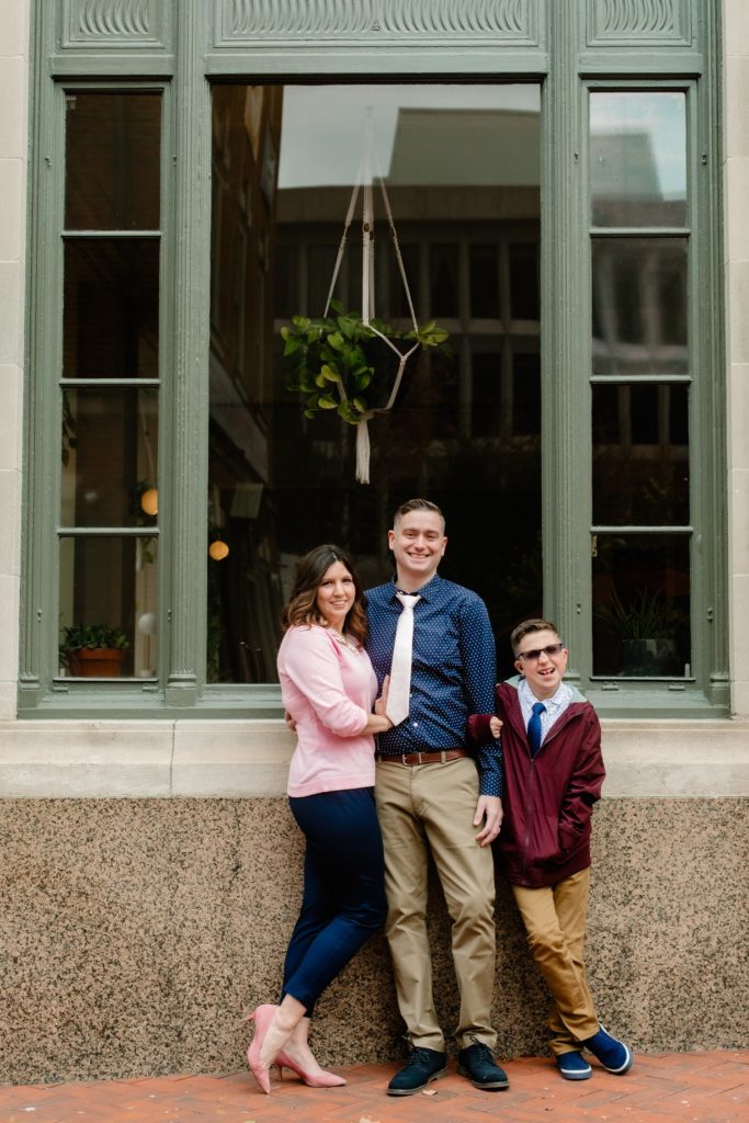 Family of three standing in front of a building smiling