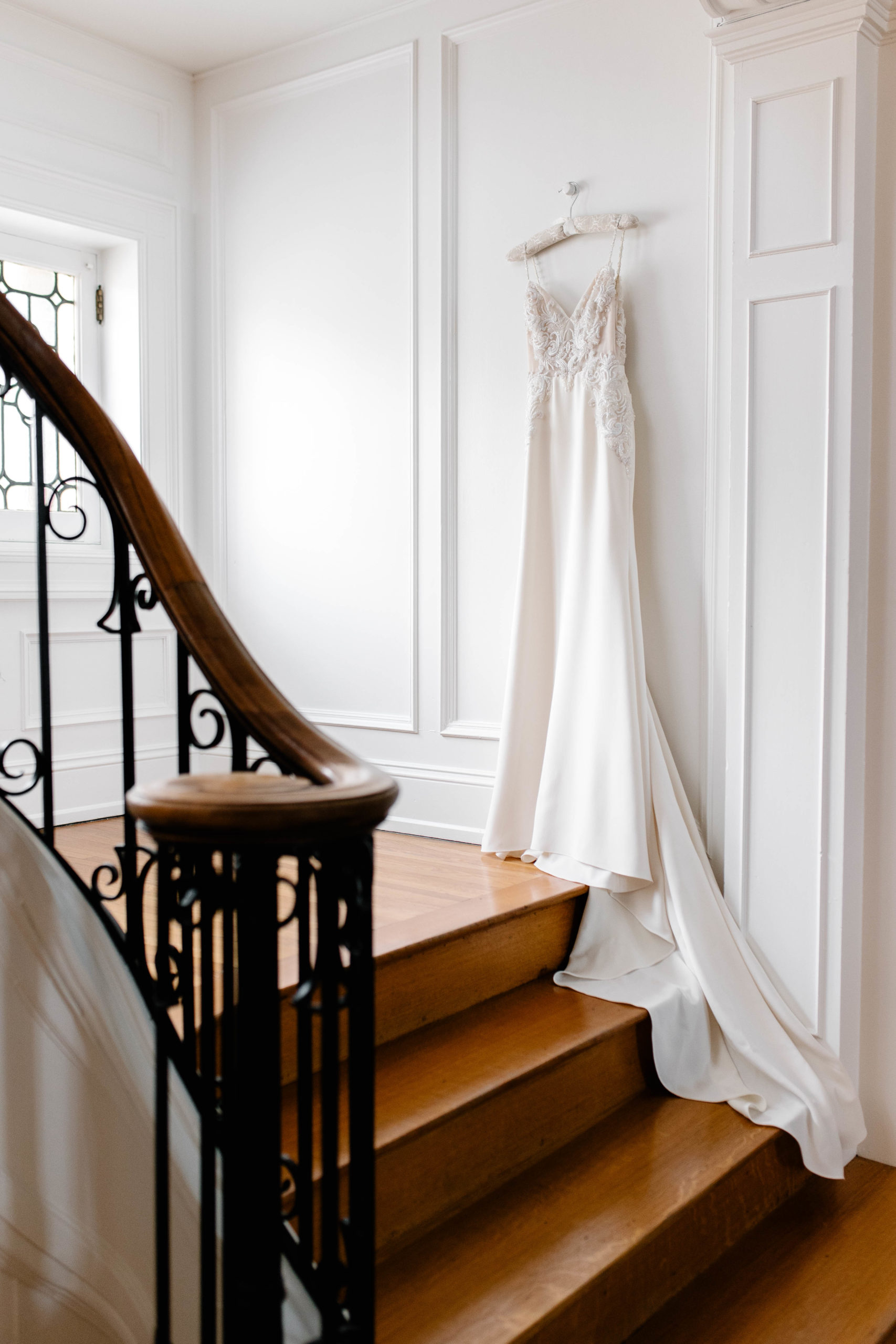 wedding dress hanging in the corner of a staircase 