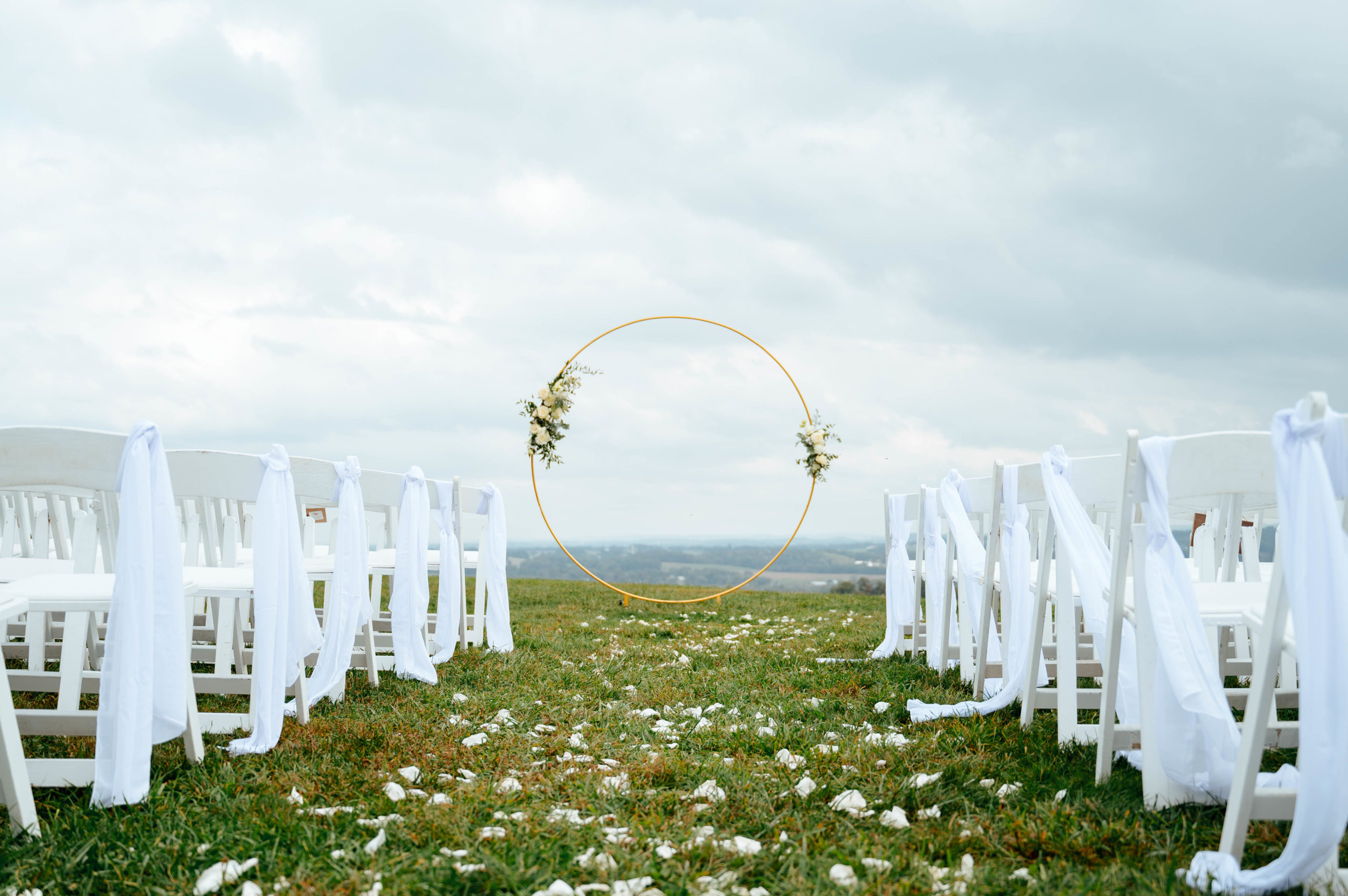 circular arch at the end of an aisle with white chairs on either side 