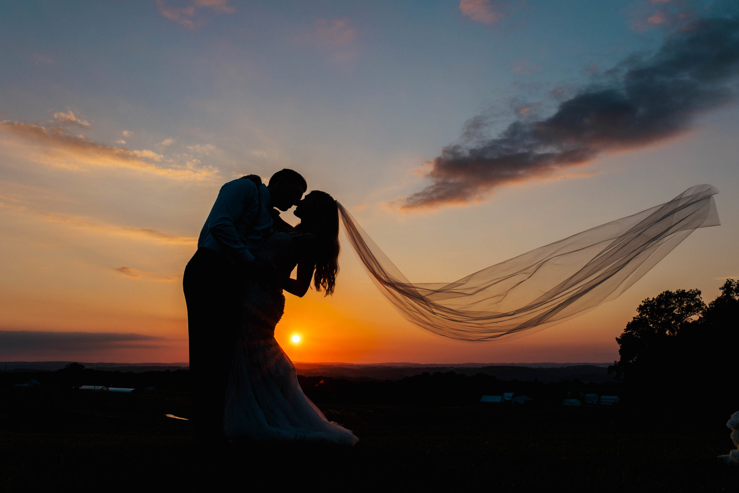 silhouette of bride and groom about to kiss at sunset 