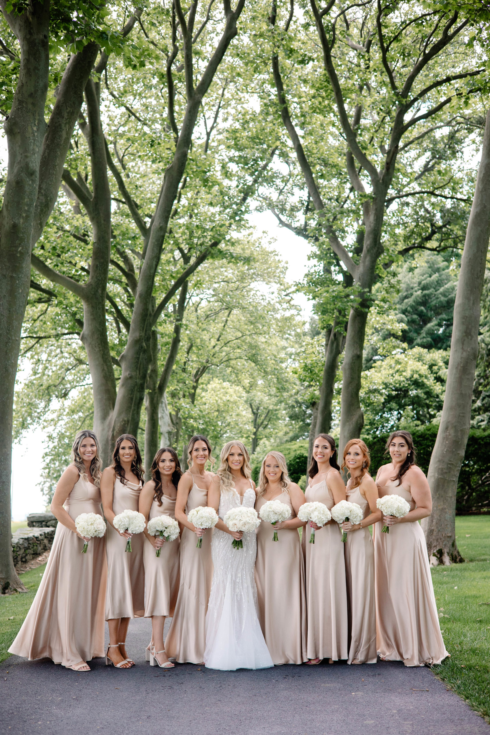 bride with wedding party surrounding them in a small treed area 