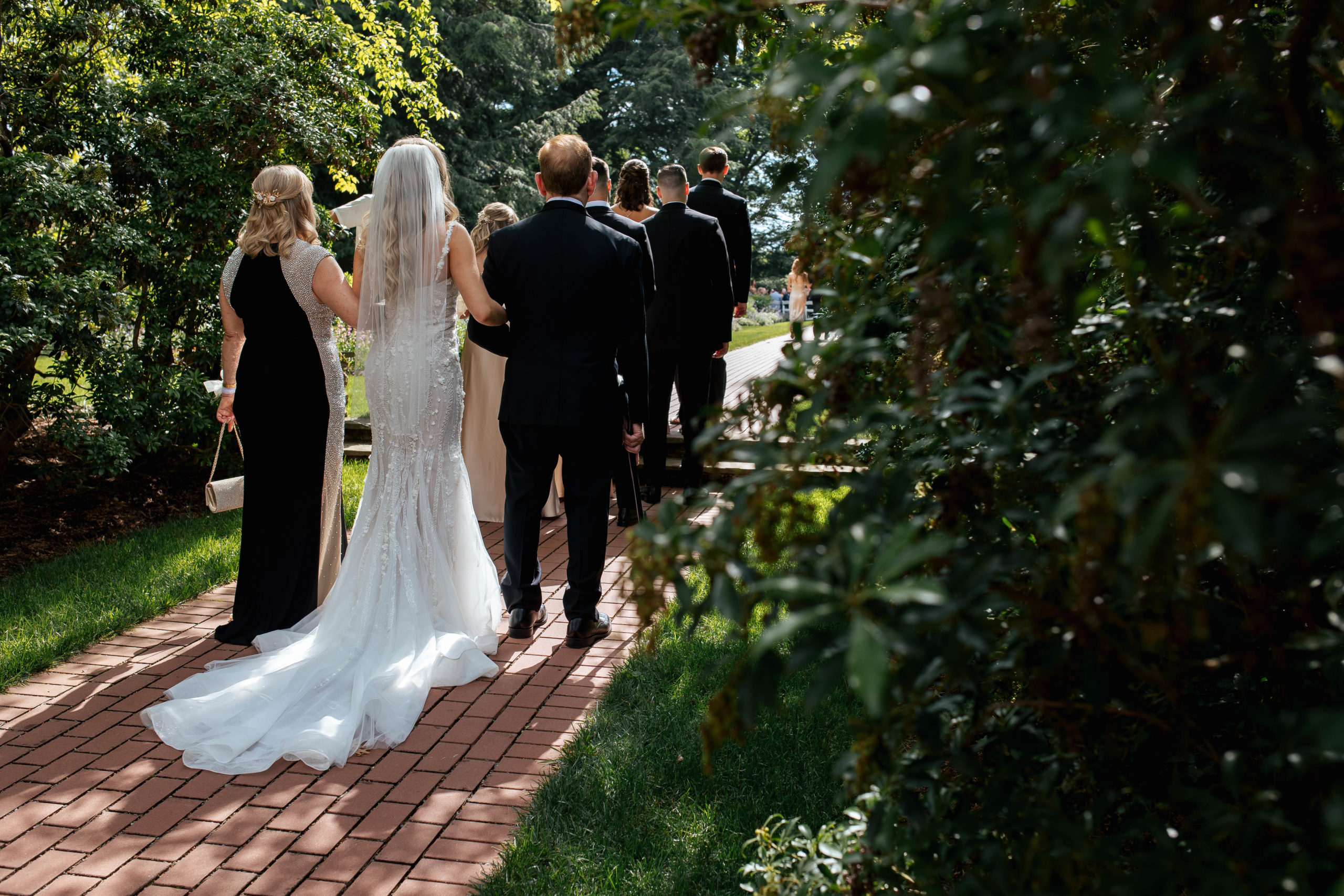 bride walking down the aisle with a man and a woman on either arm 