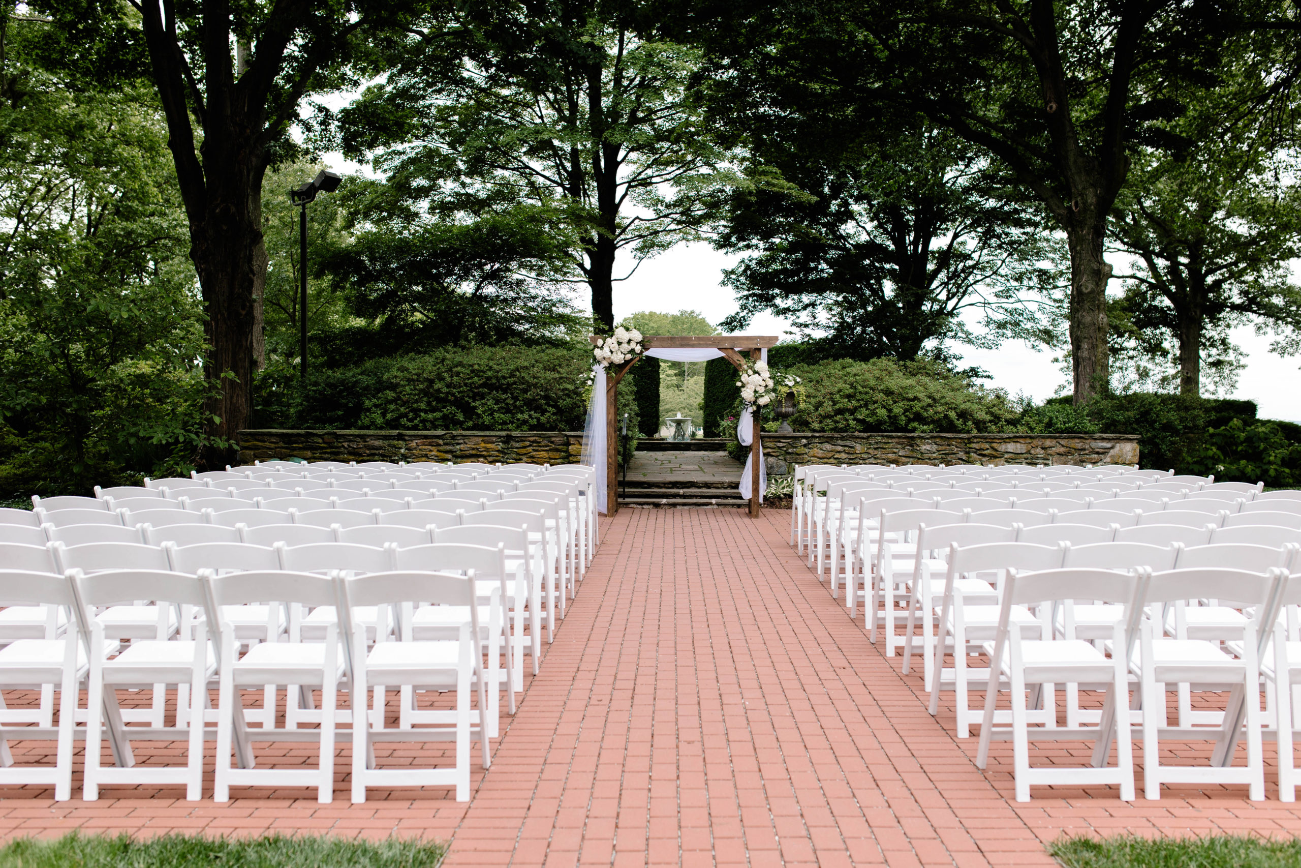 brick aisle with white chairs on either side 